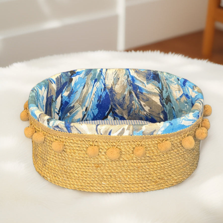 Woven organizer with blue floral lining and yellow pom-pom trim on a white surface.