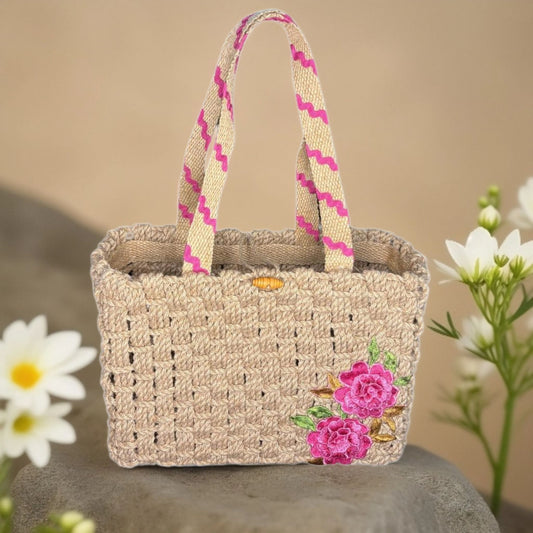 Woven handbag with floral embroidery on a stone surface with flowers in the background