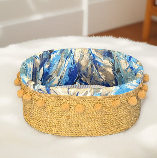 Woven organizer with blue floral lining and yellow pom-pom trim on a white surface.
