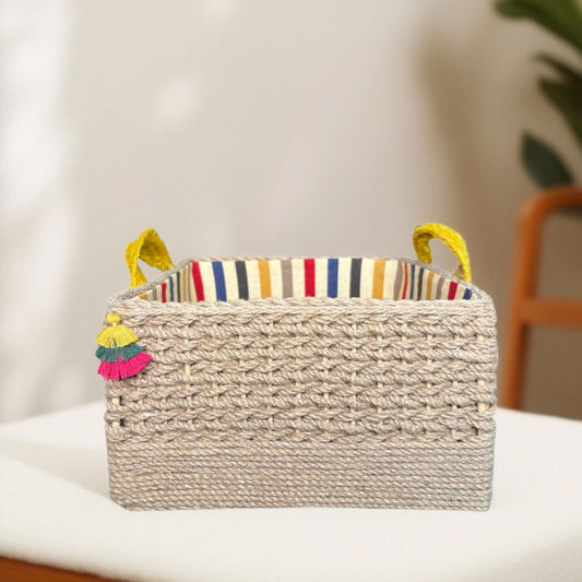 Woven storage basket with colorful striped interior and tassels on a white surface.