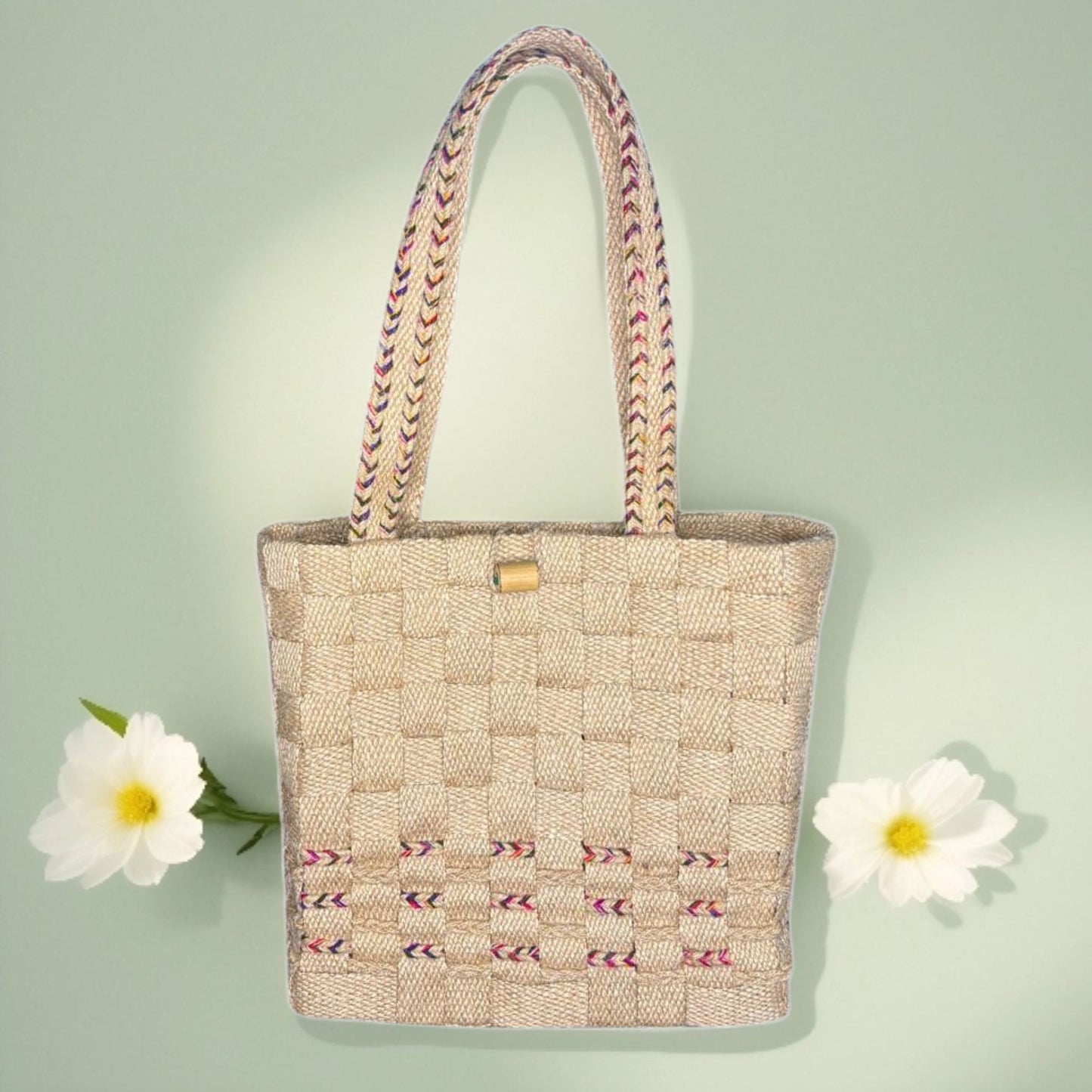 Woven handbag with embroidered design on a light green background with white flowers.